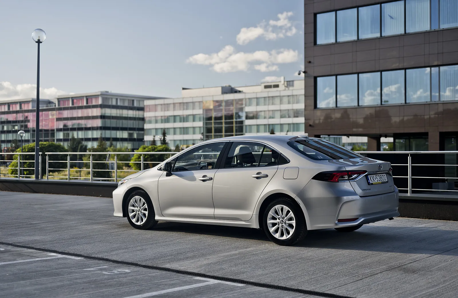 Toyota Corolla sedan hybryda z boku na parkingu