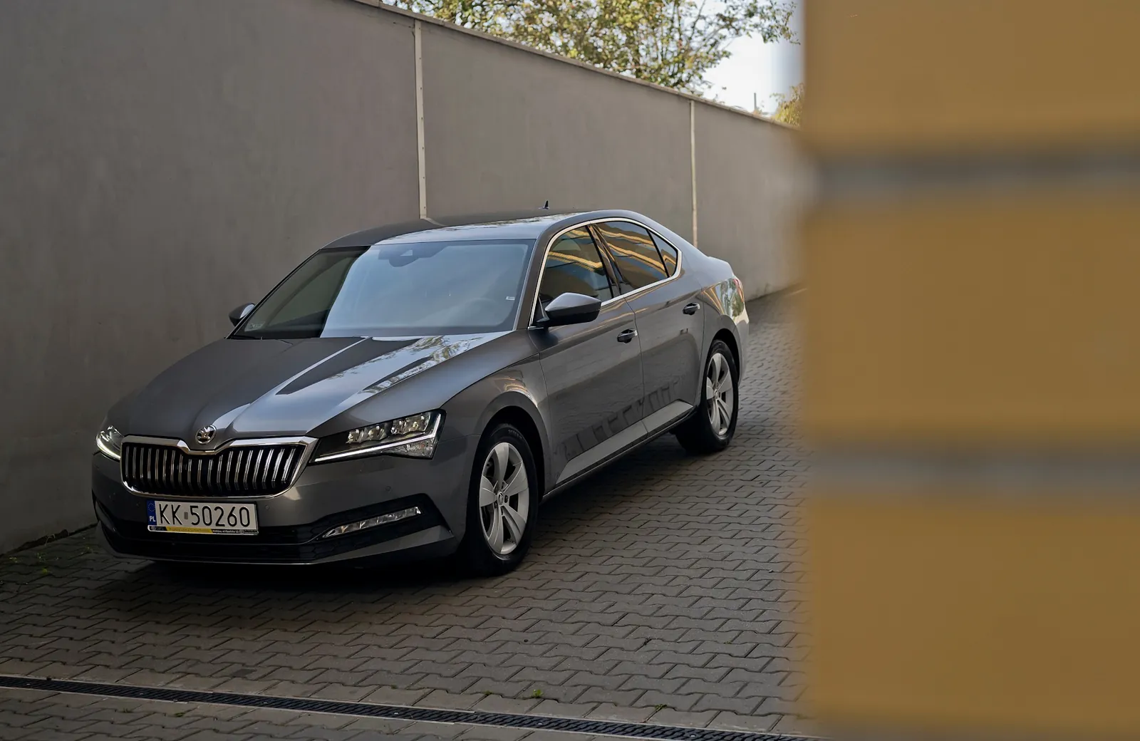 Škoda Superb z floty ANSCars zaparkowana przy murze